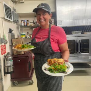 Gather staff holding two plates with salad and lasagna. 